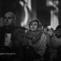 Na fotografii widoczna jest publiczność siedząca w ławkach podczas koncertu. Zdjęcie jest czarno-białe.
