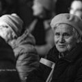 Na fotografii widoczna jest publiczność siedząca w ławkach podczas koncertu. Zdjęcie jest czarno-białe.