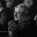 Na fotografii widoczna jest publiczność siedząca w ławkach podczas koncertu. Zdjęcie jest czarno-białe.