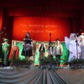 Zdjęcie przedstawia występ artystyczny uczniów z Kaszczoru na scenie, przebranych w świąteczne stroje.