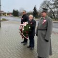 Na fotografii Janusz Frąckowiak, Wójt Gminy Przemęt, Robert Szwed, Prezes Towarzystwa Pamięci Powstania Wielkopolskiego – Koło w Przemęcie, oraz Antoni Fornalski, Honorowy Prezes Towarzystwa. Pan Antoni trzyma wiązankę, wójt oraz pan Robert stoją obok. Wszyscy oddają hołd powstańcom przy pomniku w Mochach.