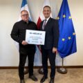 Na fotografii wójt wraz z sołtysem Nowej Wsi pozują z czekiem. W tle widoczne są flagi: Polski, Unii Europejskiej oraz z herbem gminy Przemęt.