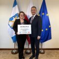 Na fotografii wójt wraz z radną Bernadetą Golińską pozują z czekiem dla Poświętna. W tle widoczne są flagi: Polski, Unii Europejskiej oraz z herbem gminy Przemęt.