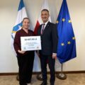 Na fotografii wójt wraz z sołtysem Siekówka pozują z czekiem. W tle widoczne są flagi: Polski, Unii Europejskiej oraz z herbem gminy Przemęt.