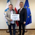 Na fotografii wójt wraz z sołtysem Wielenia pozują z czekiem. W tle widoczne są flagi: Polski, Unii Europejskiej oraz z herbem gminy Przemęt.