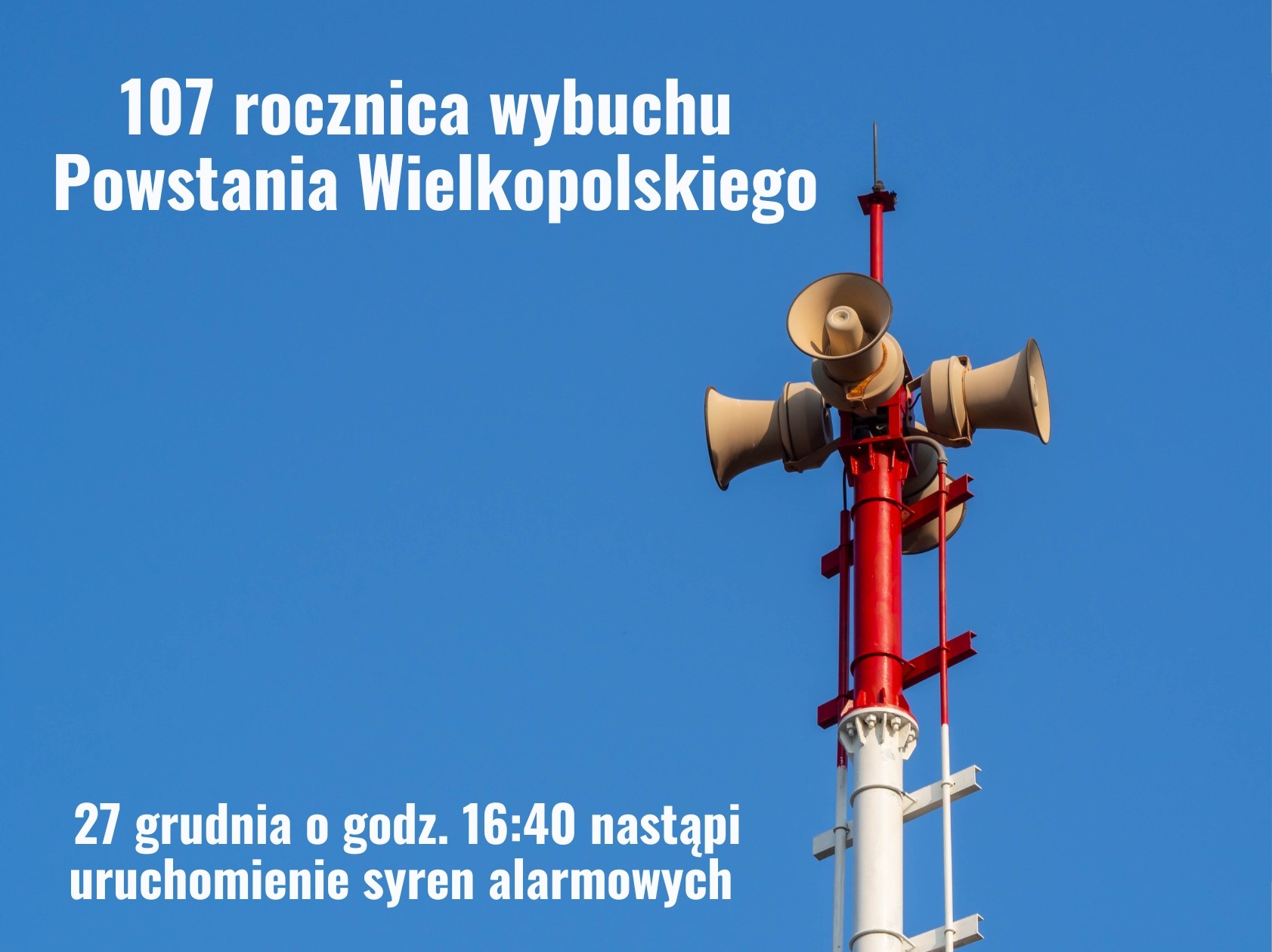 Na tle błękitnego nieba wznosi się czerwono-biały maszt z zamontowanymi głośnikami syren alarmowych. Grafika informuje o 107. rocznicy wybuchu Powstania Wielkopolskiego oraz zapowiada, że 27 grudnia o godzinie 16:40 zostaną uruchomione syreny alarmowe jako forma upamiętnienia wydarzenia.