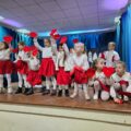 Fotografia przedstawia występ dzieci podczas finału. Dzieci w biało-czerwonych strojach prezentują układ taneczny, trzymając w rękach czerwone serduszka – symbol WOŚP.