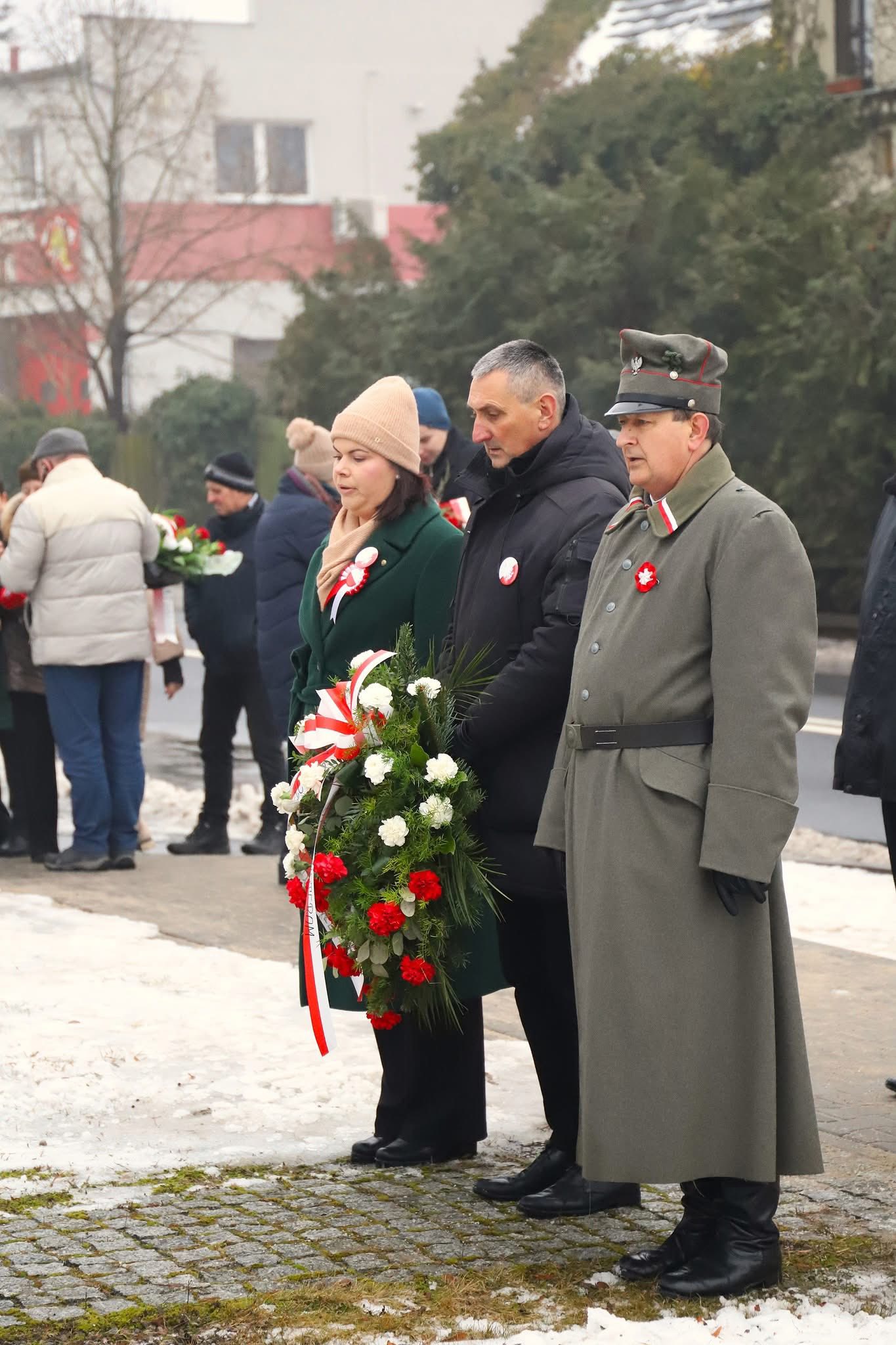 Na zdjęciu widoczna delegacja złożona z wójta Janusza Frąckowiaka, przewodniczącej rady gminy Moniki Maćkowiak oraz Prezesa Towarzystwa Pamięci Powstania Wielkopolskiego Roberta Szweda. Wójt trzyma wiązankę.