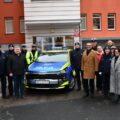 Na zdjęciu osoby uczestniczące w uroczystości pozują przy radiowozie.