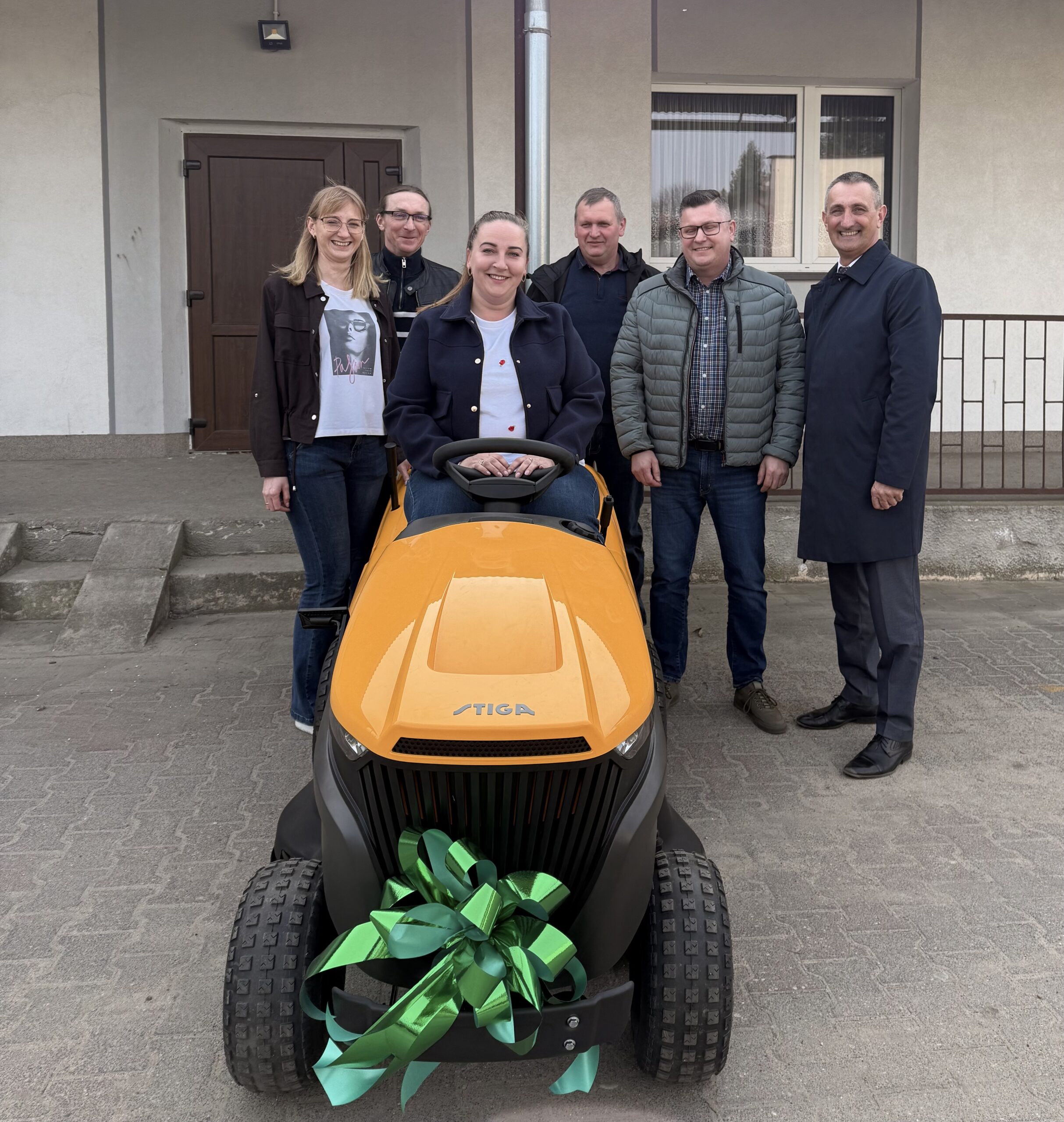 Na fotografii osoby obecne na odbiorze pozują przy nowej kosiarce.