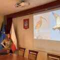 Na fotografii widoczna kobieta, która omawia prezentację wyświetlaną na projektorze.