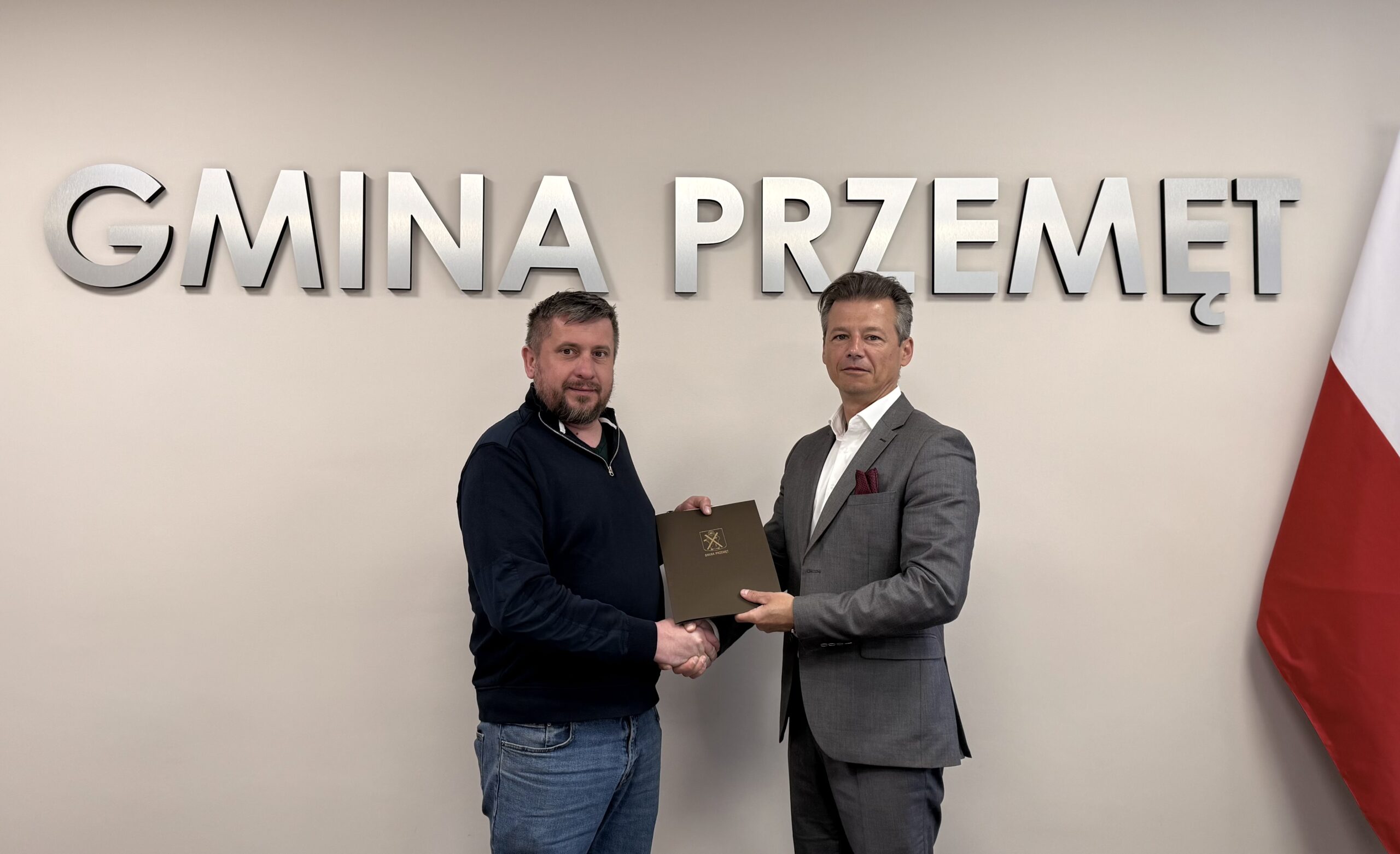 Na fotografii zastępca wójta oraz wykonawca. Pozują na tle srebrnego napisu: "Gmina Przemęt".
