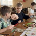 Trzech chłopców wykonuje prace plastyczne.