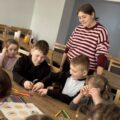 Dwóch chłopców gra w kółko i krzyżyk. Kobieta i dzieci obserwują grę.