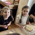 Dwie dziewczynki pozują do zdjęcia z przygotowanymi pizzami.