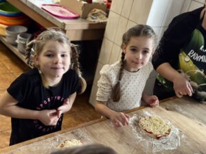 Dwie dziewczynki pozują do zdjęcia z przygotowanymi pizzami.