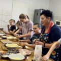 Dzieci wraz z Paniami z Koła Gospodyń Wiejskich przygotowują pizzę.