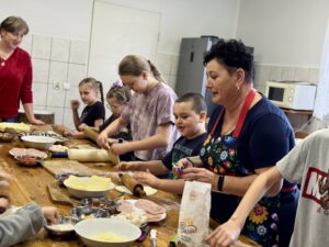 Dzieci wraz z Paniami z Koła Gospodyń Wiejskich przygotowują pizzę.