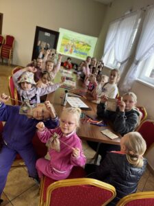 Zdjęcie grupowe. Dzieci przy stołach pozują z nowo wykonaną grą.