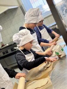 Dzieci wałkują ciasto na pizzę.