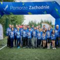 Grupowe zdjęcie zawodników klubu Azymut. Zawodnicy pozują z medalami.